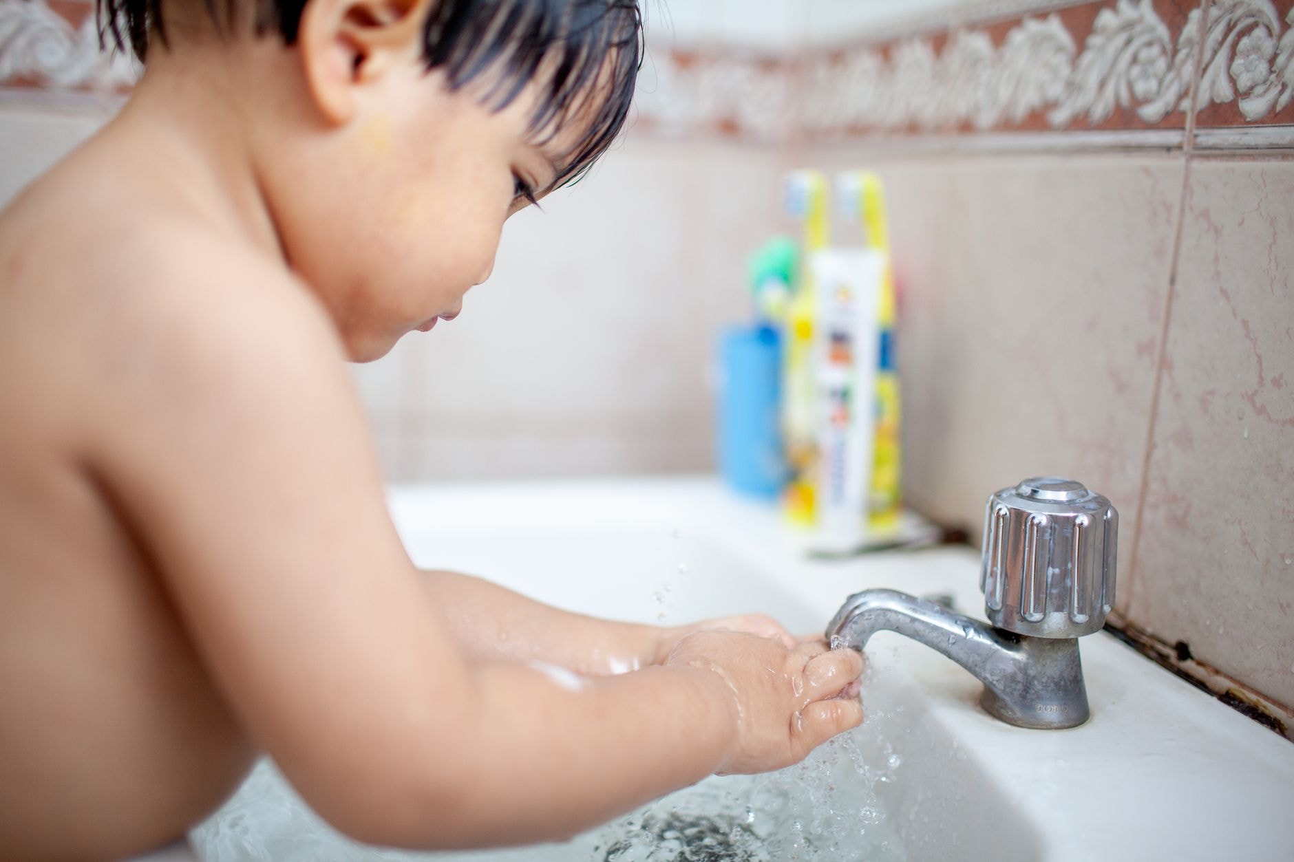 Un jeune enfant se lave les mains seul