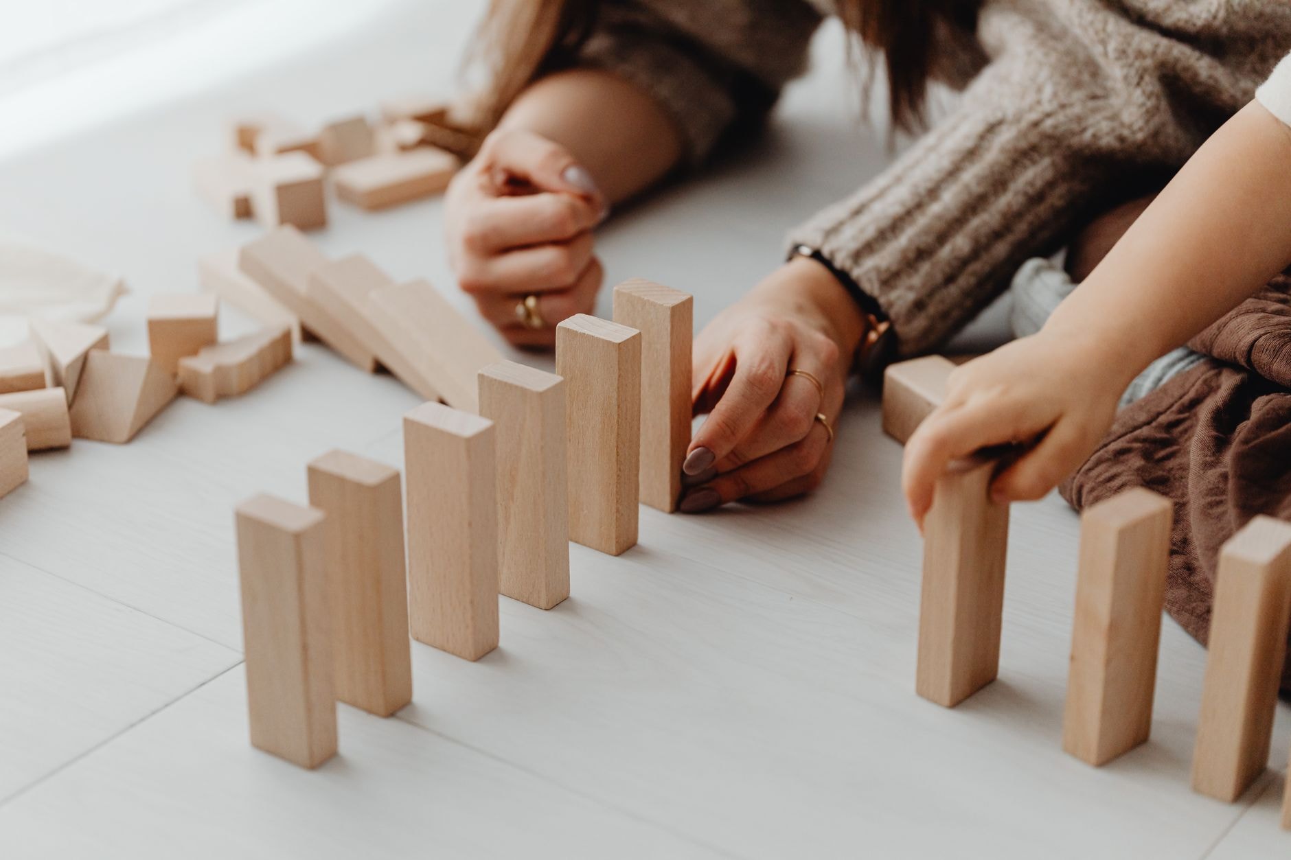 Tout-petit jouant avec des cubes en bois aux côtés d'un parent